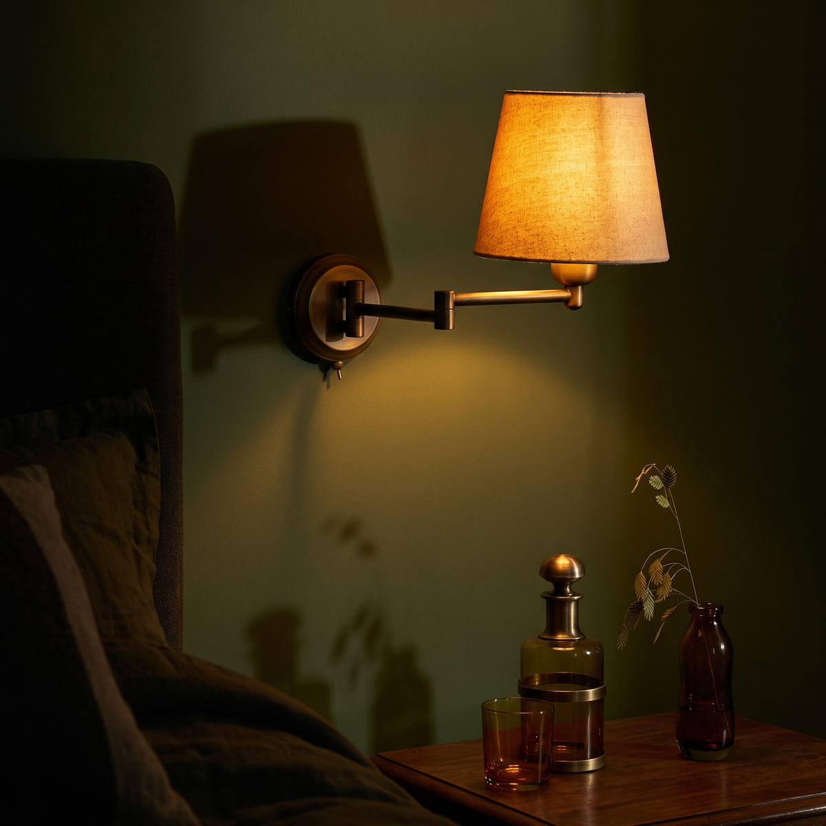 Marlow wall light lit against a deep olive green wall in the evening