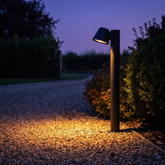 Sentry path light lit at dusk beside a gravel driveway